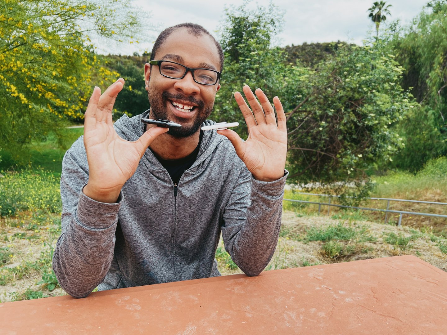 A smiling Black man communicating with two pens outdoors